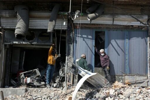 People inspect a damaged building following an airstrike in central Tehran
