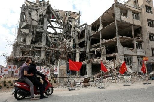 Iranians stop to look at portraits of victims reportedly killed in a US-Israeli airstrike on a residential building in Tehran