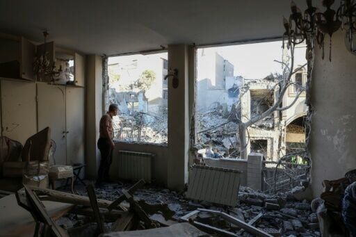 An Iranian resident looks out the window of his damaged home after Israeli-US strikes in Tehran on April 7, 2026