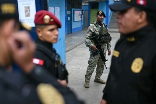 Police officers and a member of the armed forces stand guard at a school before its reopening as a polling station in Lima on April 13, 2026, after logistical failures prevented tens of thousands of people from voting in presidential and legislative ele...
