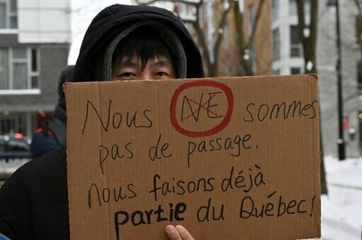 A pro-immigration demonstrator in Montreal, Canada holds a sign that reads in French: 'We're not just passing through, we're already part of Quebec'