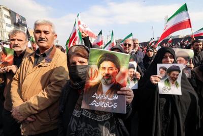 A woman poses with a picture of Iran's new supreme leader, Ayatollah Mojtaba Khamenei, in central Tehran on March 9, 2026.