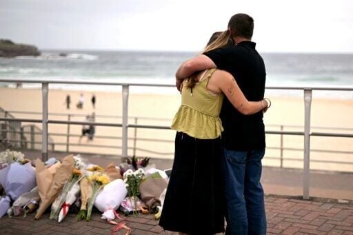 Mourners embrace near tributes piled together in memory of the victims of the Bondi Beach mass shooting.