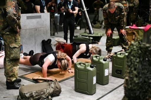 A Bundeswehr recruiter pushes interested visitors to do press-ups at the FIBO trade fair stand