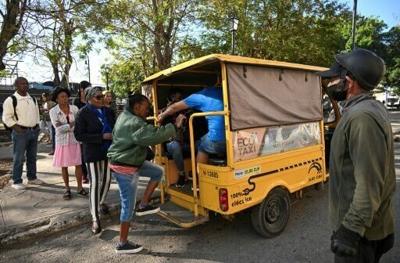 People line up to board an electric tricycle on a street in Havana