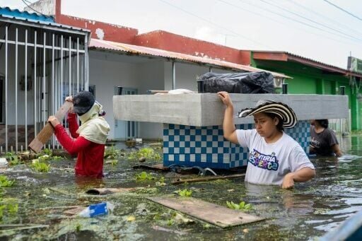 People carry belongings on a flooded street in Monteria, Colombia on February 9