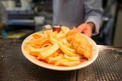 A chef poses with a plate of fish and chips at Poppies fish and chip restaurant in east London