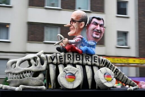 Effigies of German Chancellor Friedrich Merz (L) and Bavarian leader Markus Soeder driving a skeleton marked 'combustion engine' for weakening car pollution laws