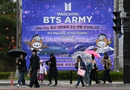Pedestrians walk in front of a banner welcoming BTS fans near a stadium where K-pop boy band BTS will perform in Goyang on April 9, 2026.