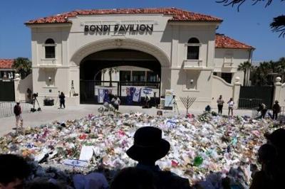 Mourners stand near tributes piled together at the front of the Bondi Pavilion, in memory of the victims of the Bondi Beach shooting