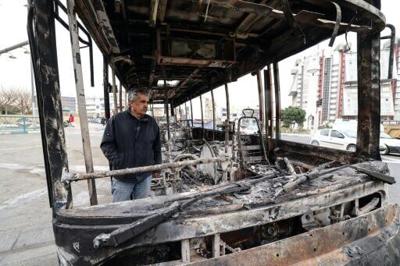 A man stands in the wreckage of a burned bus in Tehran's Sadeghieh Square on January 15, 2026
