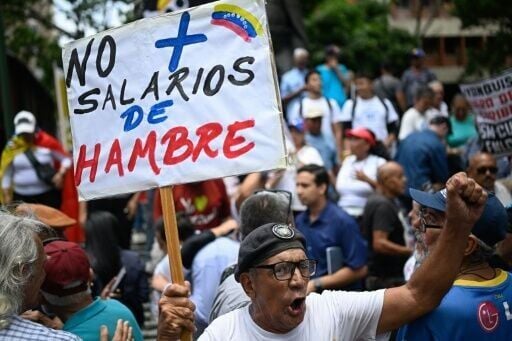A man holds a sign reading 'No more starvation wages' during a May Day rally in Caracas