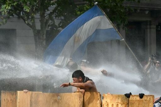 Argentine demonstrators are hit by water cannon fired by riot police during a protest in Buenos Aires against proposed labor reforms