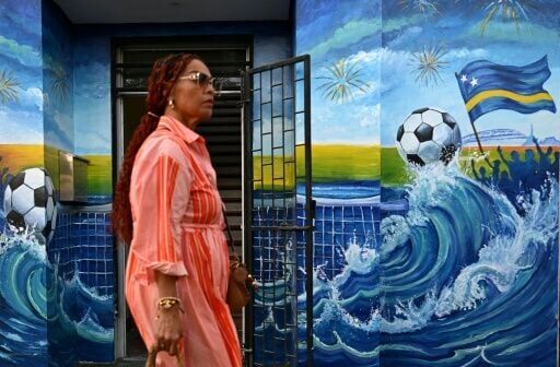 A woman walks past a mural depicting a football and the flag of Curacao in Willemstad, capital of the Dutch Caribbean island which is gripped by World Cup fever