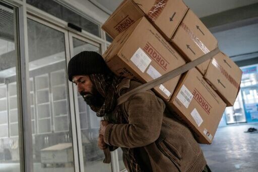A worker carries pharmaceuticals imported from India into a shop in Kabul