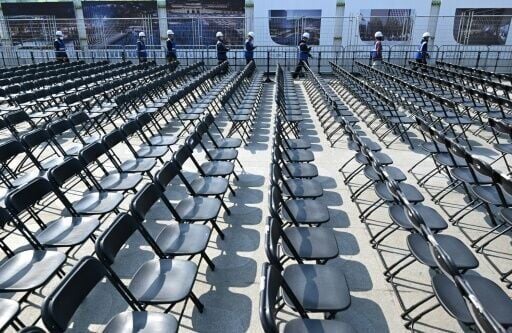 Workers walk past rows of chairs set up for the comeback concert of K-pop boy group BTS at Gwanghwamun Square in Seoul on March 20, 2026.