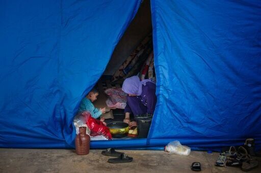 A woman cooks inside a tent at a stadium in the Lebanese capital Beirut converted into a shelter for people displaced by the conflict
