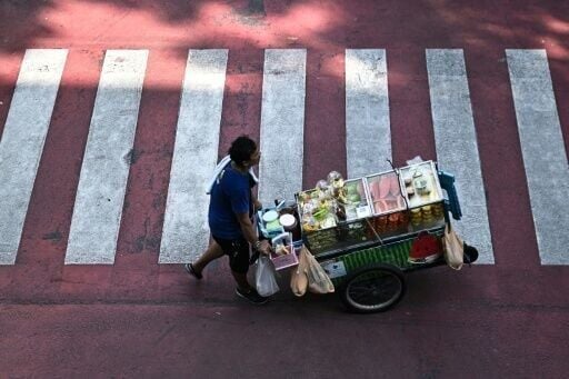 A street vendor pushes a cart of fresh fruit in Bangkok, where tighter controls on vendors threaten livelihoods and the street food culture that defines the Thai capital