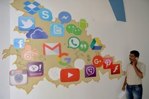 A man passes by a mural depicting various social media apps in Bangalore on March 22, 2018
