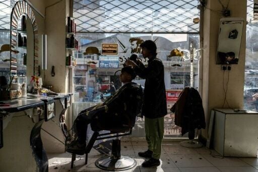 An Afghan barber attends to a customer at a salon in Kabul