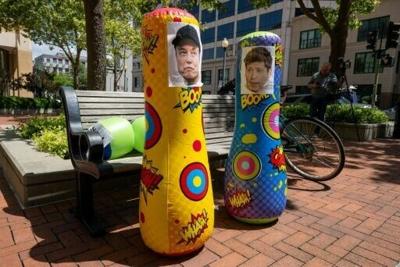 Punching bags with the faces of AI founders Elon Musk and Sam Altman are placed in front of a federal courthouse in Oakland, California