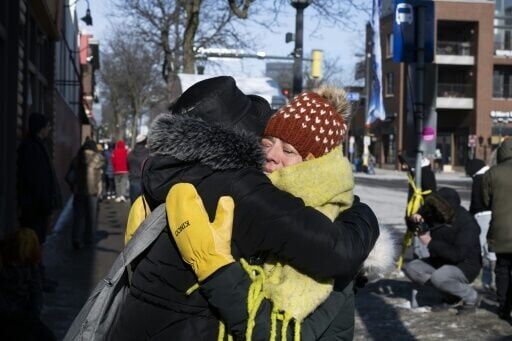 Two women hug at a makeshift memorial in the area where Alex Pretti was shot dead by federal immigration agents in Minneapolis, Minnesota, on January 26, 2026