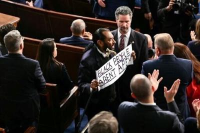 US Representative Al Green, a Democrat from Texas, holds a sign reading "Black people aren't apes!" as President Donald Trump delivers his State of the Union address in the House chamber of the US Capitol in Washington