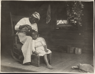 Sharecropper in 1900s braiding child's hair
