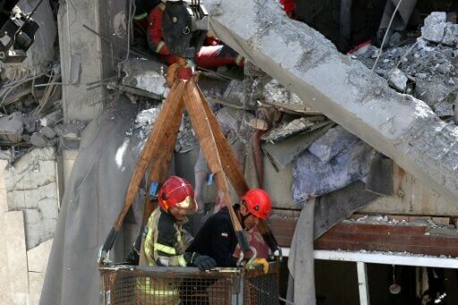 Firefighters try to recover the body of a victim in a damaged building in southern Tehran