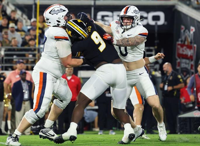Virginia offensive guard Noah Josey (77) and Virginia tight end Sage Ennis (0) block Mizzou defensive end Zion Young (9)