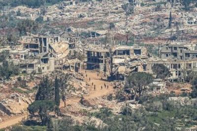 Israeli soldiers walking along the road between destroyed houses in southern Lebanon