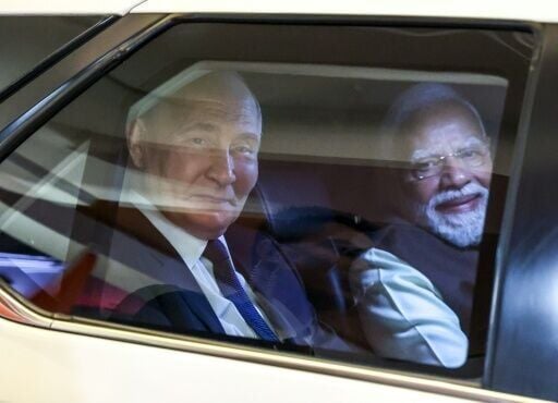 In this pool photograph distributed by the Russian state agency Sputnik, Russia's President Vladimir Putin and Indian Prime Minister Narendra Modi look out from a car prior to an informal dinner at Modi's residence