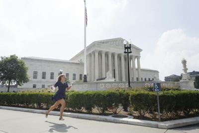 A news reporter carrying printed justice opinion announcements sprints outside U.S. Supreme Court on June 29, 2026, in Washington, DC.