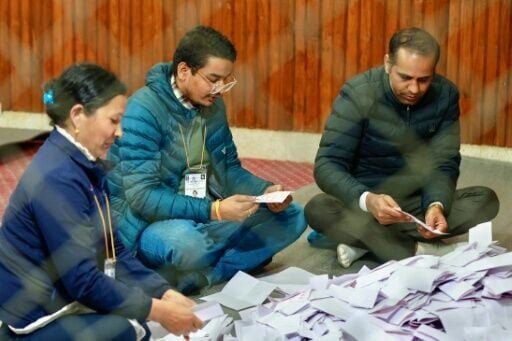Election officials sit on the floor as they tally votes at a counting centre in Kathmandu