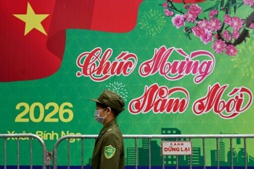A security guard walks past a New Year's greeting banner in Hanoi
