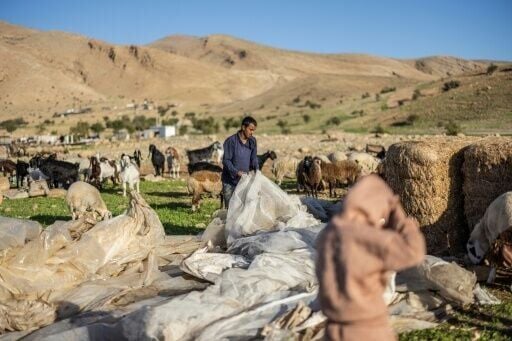 A Bedouin man gathers plastic sheeting as families begin to collect their belongings to leave their homes after harassment from Israeli settlers in Ras Ein al-Auja