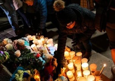 Community members place flowers during a vigil to honor the victims of the Tumbler Ridge mass shooting