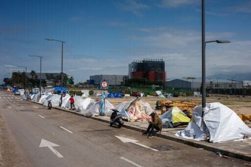 Displaced families sit next to their tents covered with plastic sheets to shield from stormy weather in Beirut