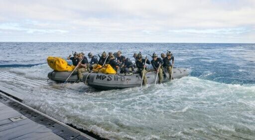 This handout image released by NASA shows US Navy divers preparing to deploy from the well deck of the USS John P. Murtha to recover Artemis II astronauts and the Orion spacecraft after it splashed down in the Pacific Ocean near California