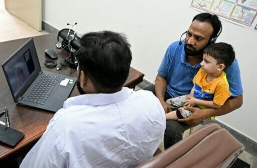 Muhammad Adil (with child) receiving an online and free doctor consultation for his son at a clinic of digital health firm Sehat Kahani in Karachi