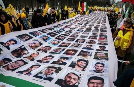 At the MEK demo, protesters display a banner featuring portraits of alleged victims of the Iranian government