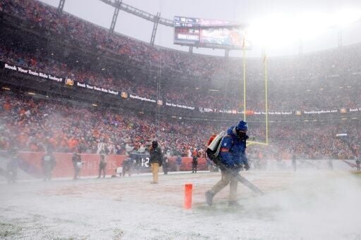 Workers attempt to clear snow from the field during New England's blizzard-hit victory over Denver