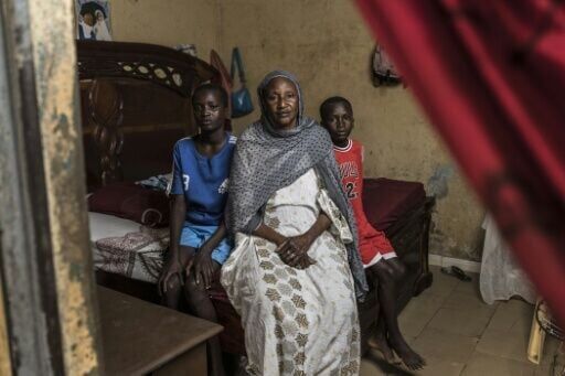 Ndeye Ndiaye (C) sits with her grandsons Fallou (L) and Bara (R) at her home in Mbour