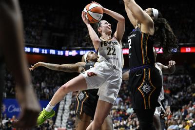 Indiana Fever guard Caitlin Clark (22) is fouled from behind by Connecticut Sun guard Tiffany Mitchell (3) as she drives against forward Brionna Jones (42.)