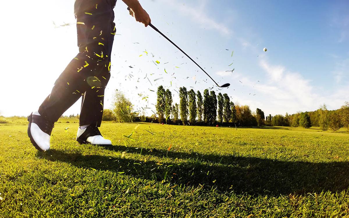 Golfer performs a golf shot from the fairway.