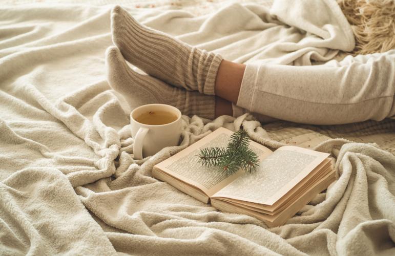 Cozy Winter Evening , Warm Woolen Socks. Woman Is Lying Feet Up On White Shaggy Blanket And Reading