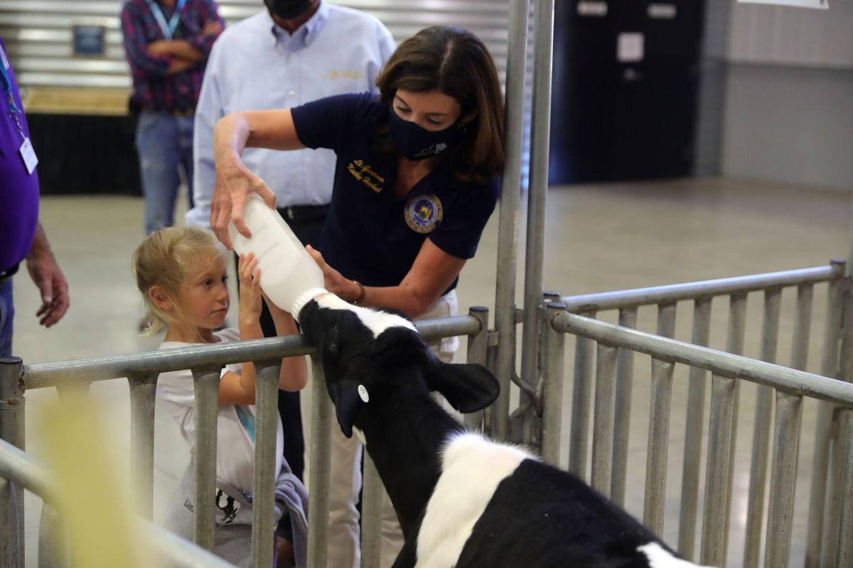 Liv Ennis, 6, of Genesee, and Kathy Hochul, lieutenant governor of New York give a bottle to a calf