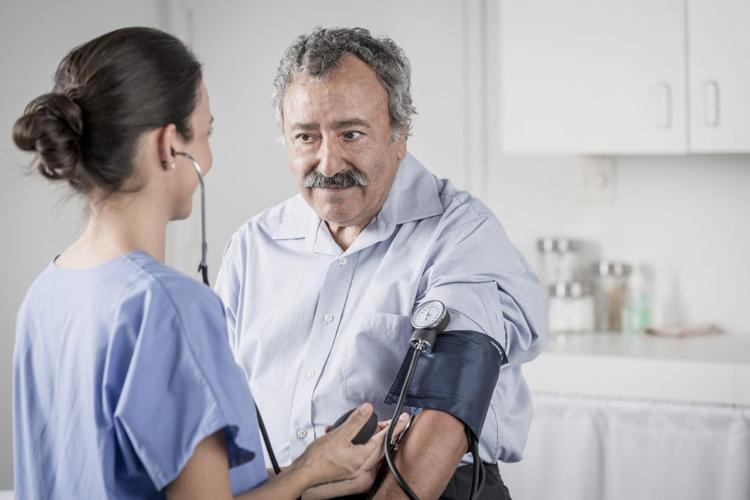 Nurse checking senior man’s blood pressure