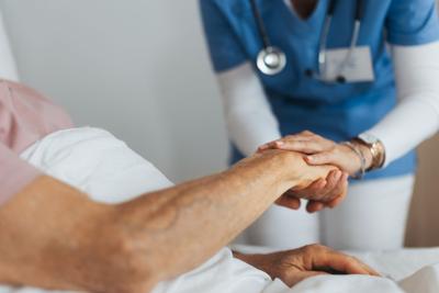 Close-up of caregiver holding senior client hand.