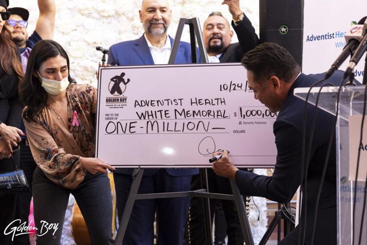 De La Hoya signing the check for his donation – Courtesy of Golden Boy Promotions